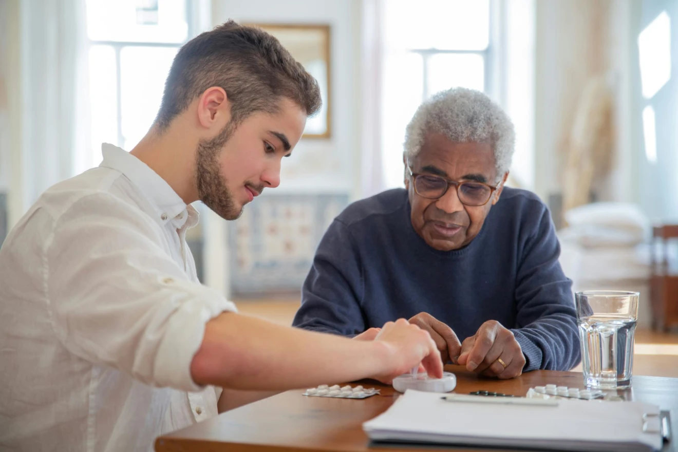 Ältere Person wird im Pflegeheim von einer pflegenden Person betreut. Sie füllen gemeinsam Tabletten in eine tragbare Tablettenbox.
Foto: Kampus Production